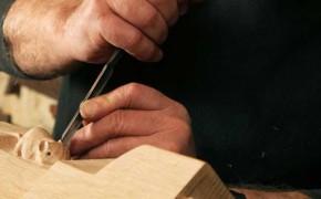 Close-up of a sculptor carving a mouse on a piece of furniture