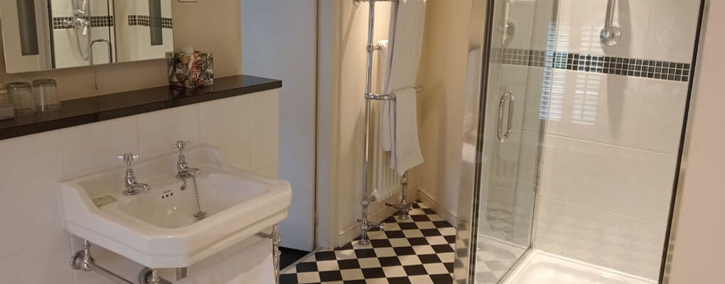 Montage of the en-suite bathroom, showing walk-in shower room, showing the mirror, the shower head, the glass shower door, and the basin.