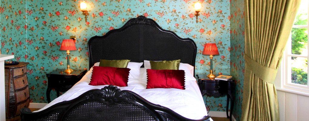 King double bed, ornate black headboard and footer red and gold cushions