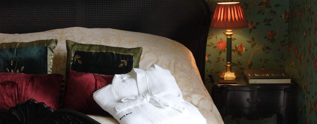 Close view of left side of king double bed, with quality white bath robe neatly folded and placed beside the pillow.